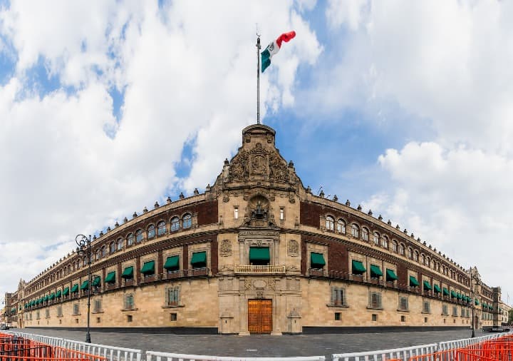palacio nacional visto desde frente y con bandera mexicana y cielo con nubes, algo que ver en ciudad de mexico