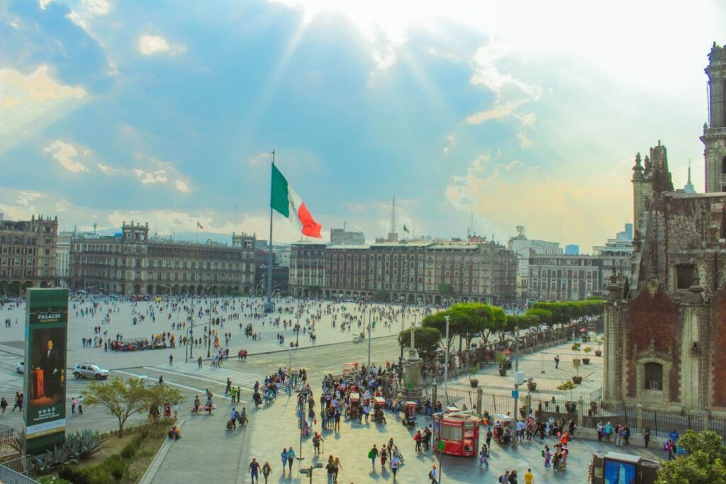 plaza de la consititucion con edificios, gente y bandera mexicana en el centro, ciudad de mexico