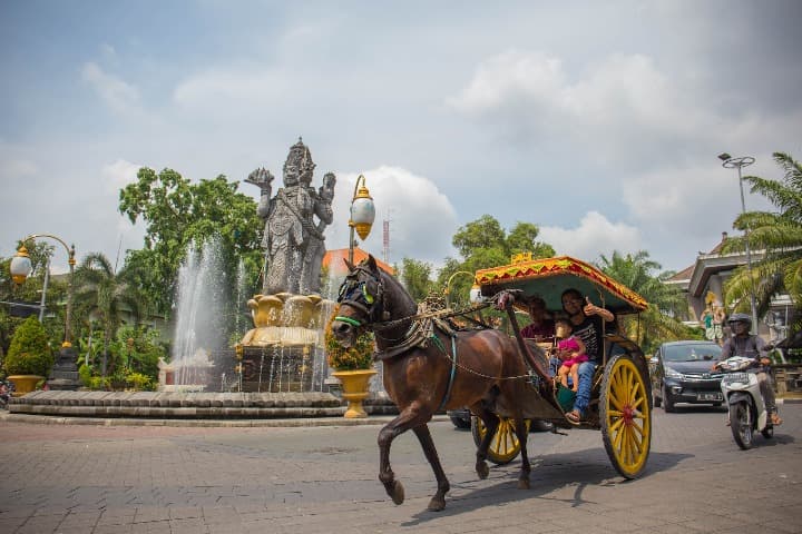 tuk tuk con caballo y estatua detrás en una plaza de bali, uno de los mejores destinos para nómadas digitales