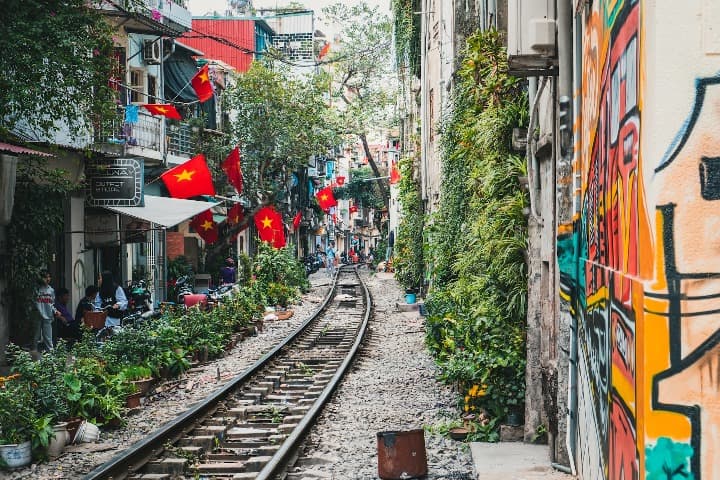 vias del tren en hanoi, vietnam con edificios con banderas a los lados. este país es uno de los destinos de viajes que hacer antes de los 40