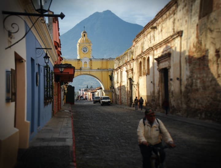 arco con reloj, calle y montaña al fondo en antigua guatemala