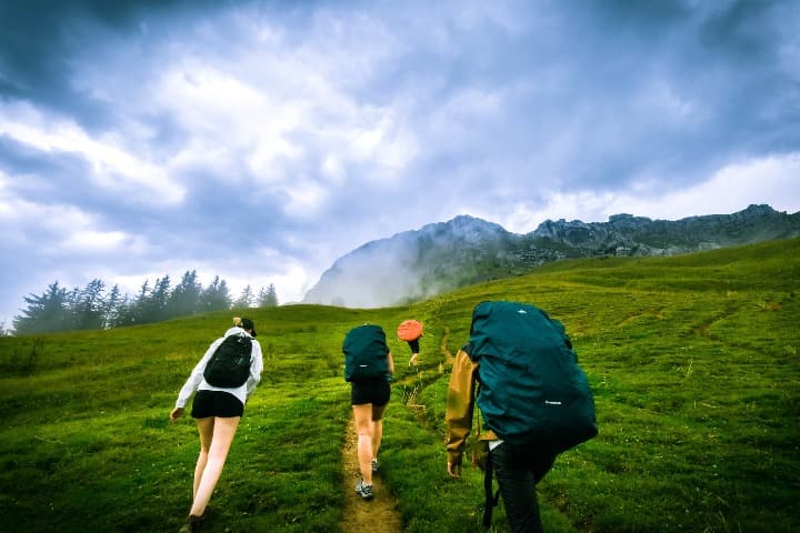 personas con mochila caminando en medio de la montaña