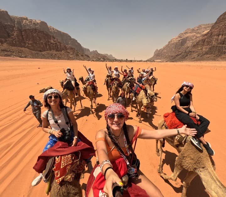 selfie de viajeros de weroad en el desierto, encima de camellos en jordania