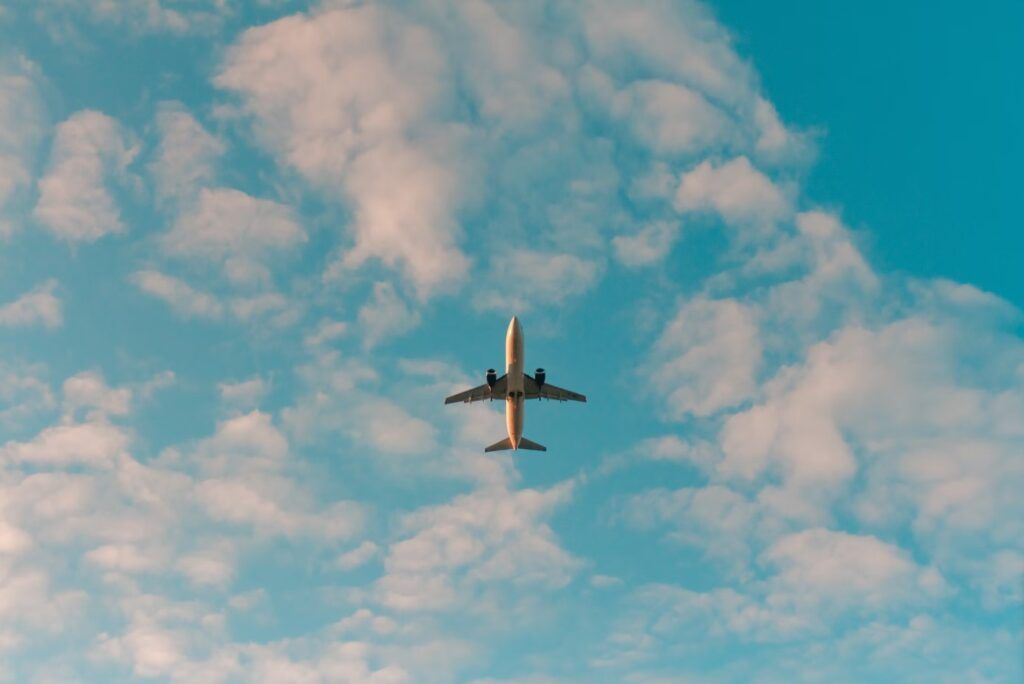 avion visto desde tierra en medio al cielo con nubes, cuando es mas barato comprar un vuelo
