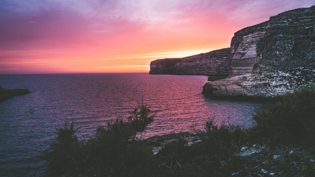 puesta del sol a gozo, frente al mar con rocas de fondo