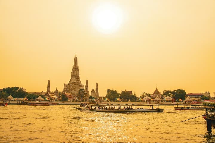 paisaje de bangkok con luz amarilla, templo y long tail en el agua