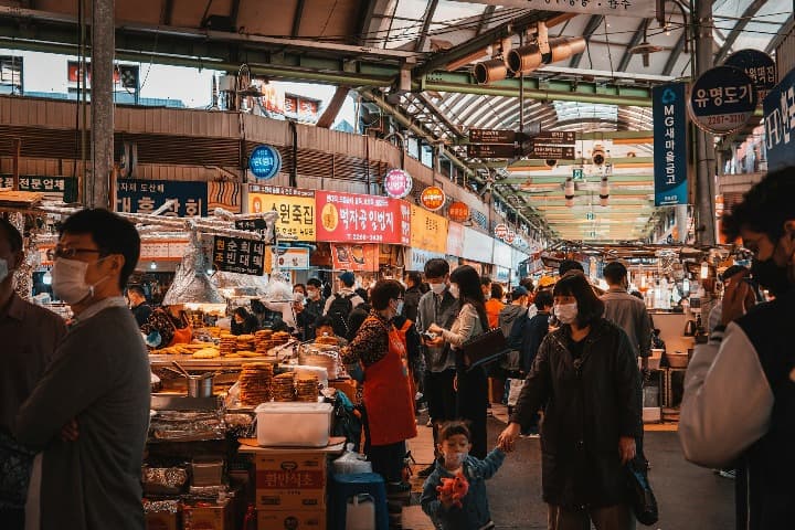 parada en el interior del mercado de Gwangjang, en seul. personas caminando y comida callejera expuesta