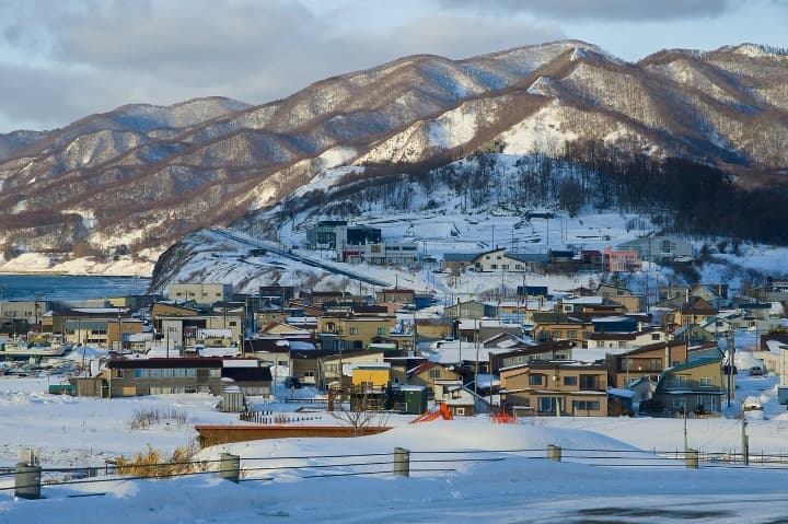 paisaje de montaña con nieve y casas en hokkaido, japón