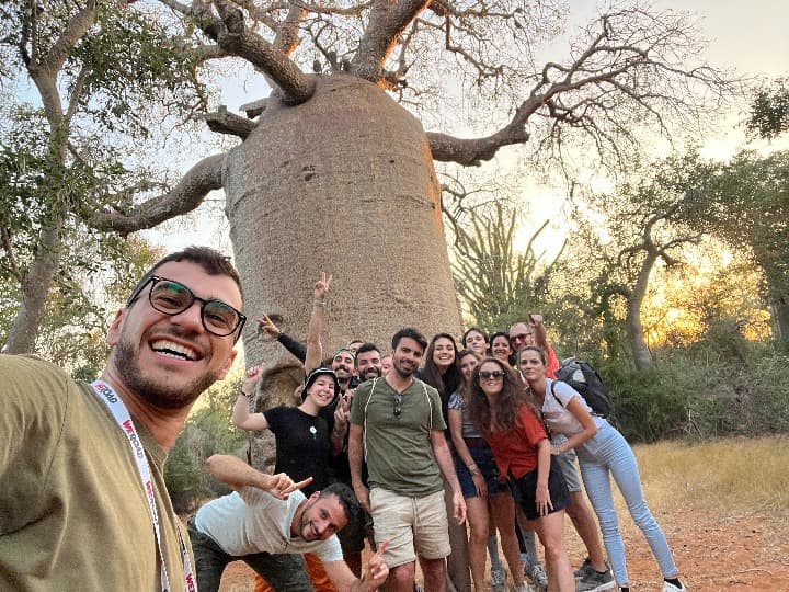 selfie de grupo de viajeros de weroad delante de un baobab, arbol que ver en madagascar