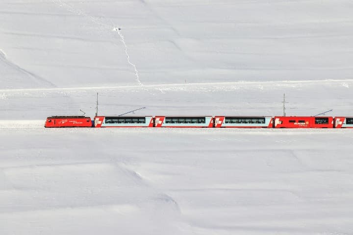 glacier express, tren blanco y rojo en medio de nieve, uno de los viajes en tren mejores que hacer en europa