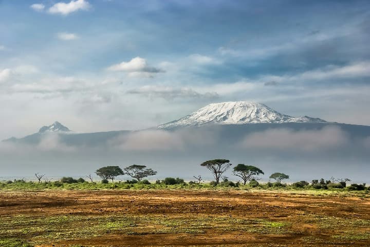 sabana en kenia con montañas y arboles, destino a donde viajar en marzo