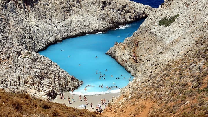 playa de Seitan Limania en medio de rocas, gente bañandose y en la arena