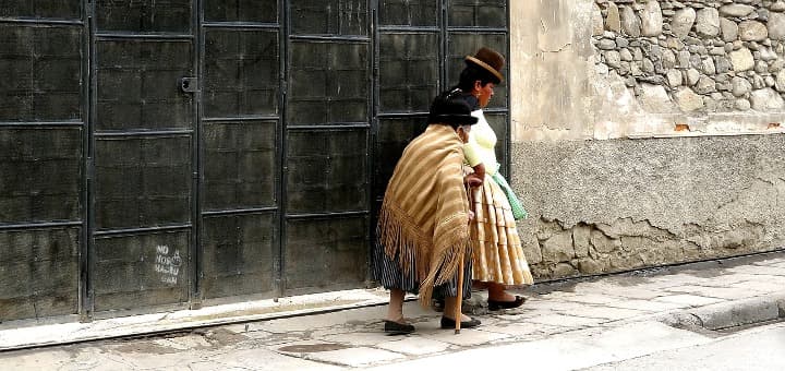 dos mujeres caminando por calle de la paz vestidas de forma tradicional