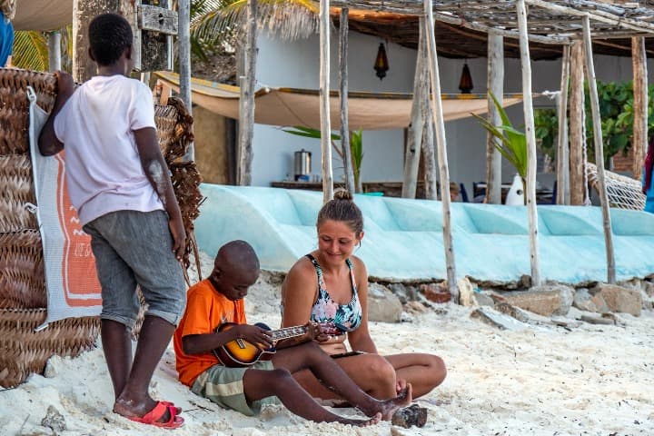 niños jugando con una chica en la playa, mejor época para viajar a zanzíbar