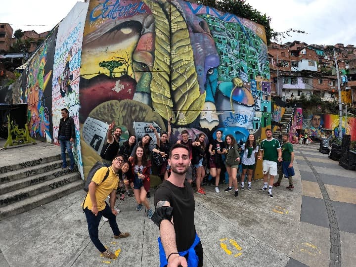 selfie de grupo delante de edificio con graffiti con graffiti en la comuna 13 en medellín