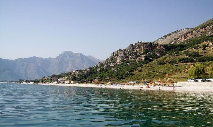 montañas al fondo y playa, agua en primer plano en borsh, una de las playas de albania que visitar