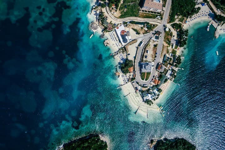 ksamil vista desde el cielo, playa y mar azul, edificios y carretera en el espigón