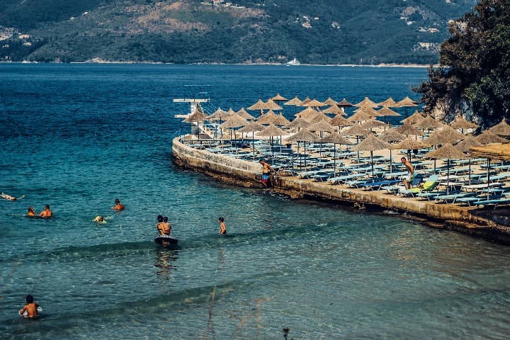 espigón con sobrillas y tumbonas y gente en el agua en saranda beach