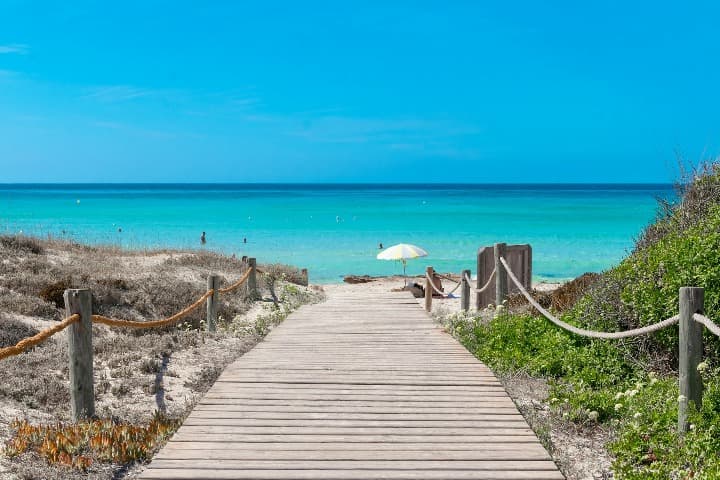 pasarela que lleva a mar y cuelo azules, sombrilla