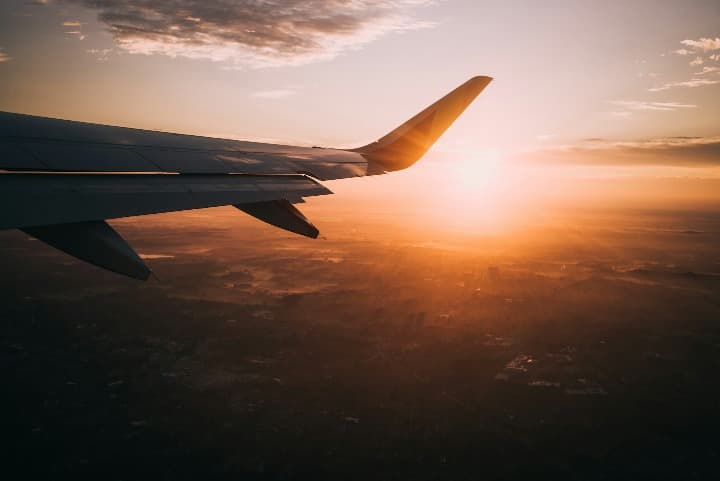 ala de avion, puesta del sol al fondo, destinos a donde viajar en junio