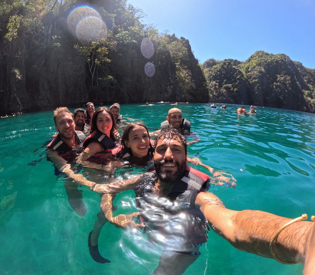 Grupo de viajeros de Weroad disfrutando mientras nadan en las aguas claras de una laguna durante un viaje en grupo a Filipinas.