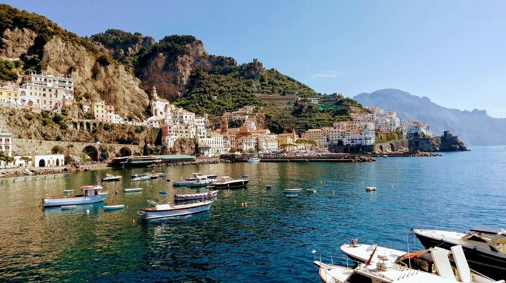 Paisaje pintoresco de la Costa Amalfitana con casas coloridas y barcos en el puerto.