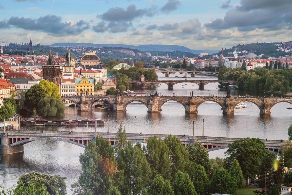 Vistas de los puentes históricos de Praga sobre el río Moldava con un cielo nublado.