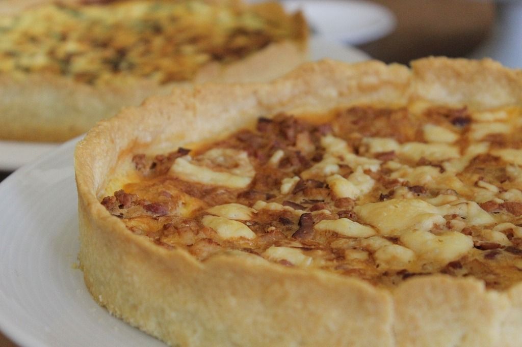 Quiche lorraine con queso y tocino en una base crujiente de masa.