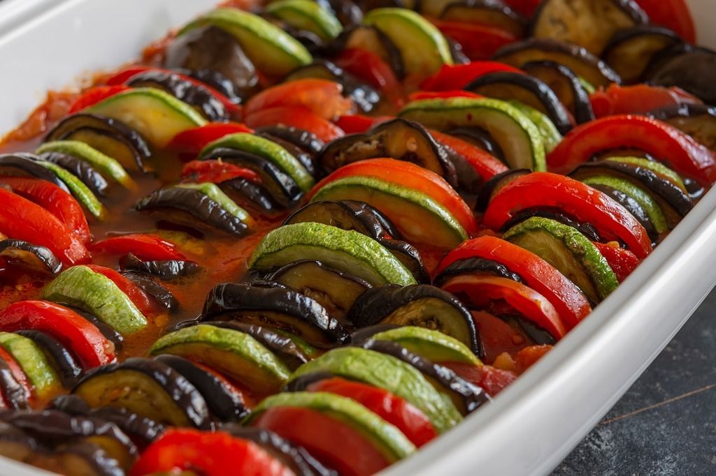 Plato de ratatouille con rodajas de calabacín, berenjena y tomate perfectamente cocinados.