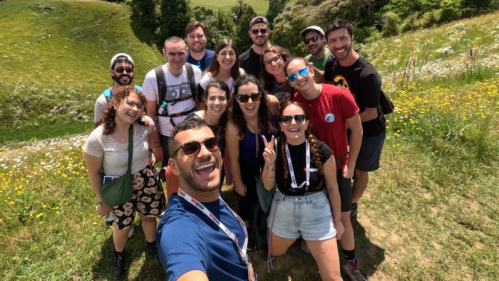 Grupo de viajeros felices durante un tour organizado por WeRoad en un paisaje verde y florido en Polonia.