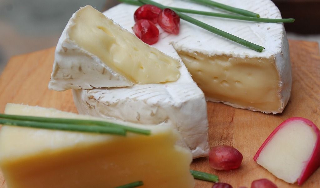 Ruedas de queso brie francés decoradas con granadas y cebollín fresco.