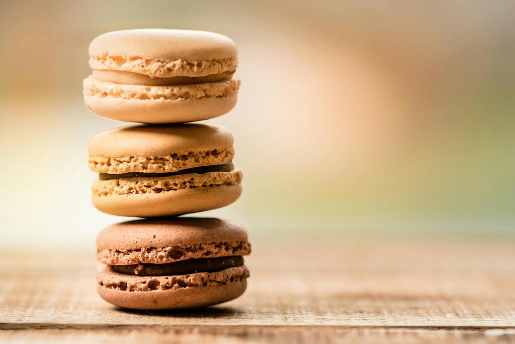 Macarons franceses apilados en una mesa de madera con un fondo difuminado.