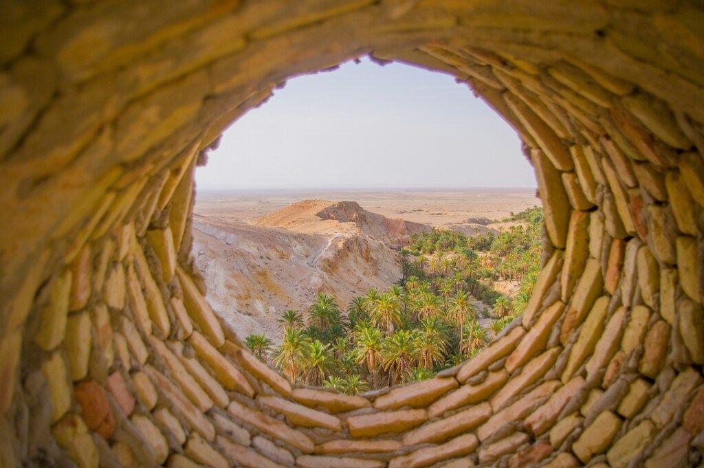 Vista del desierto y oasis a través de una abertura de piedra