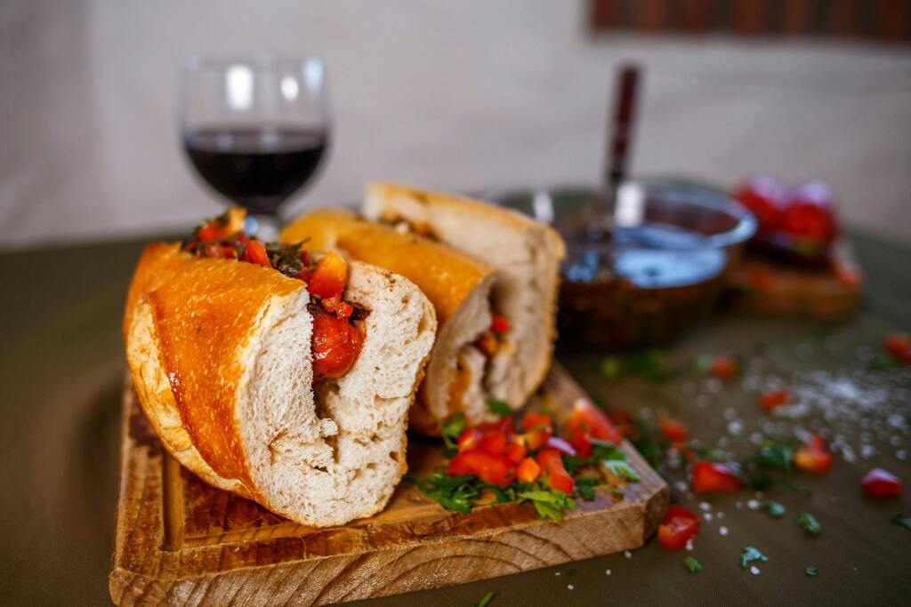 Sandwich artesanal relleno con verduras frescas y vino tinto al fondo
