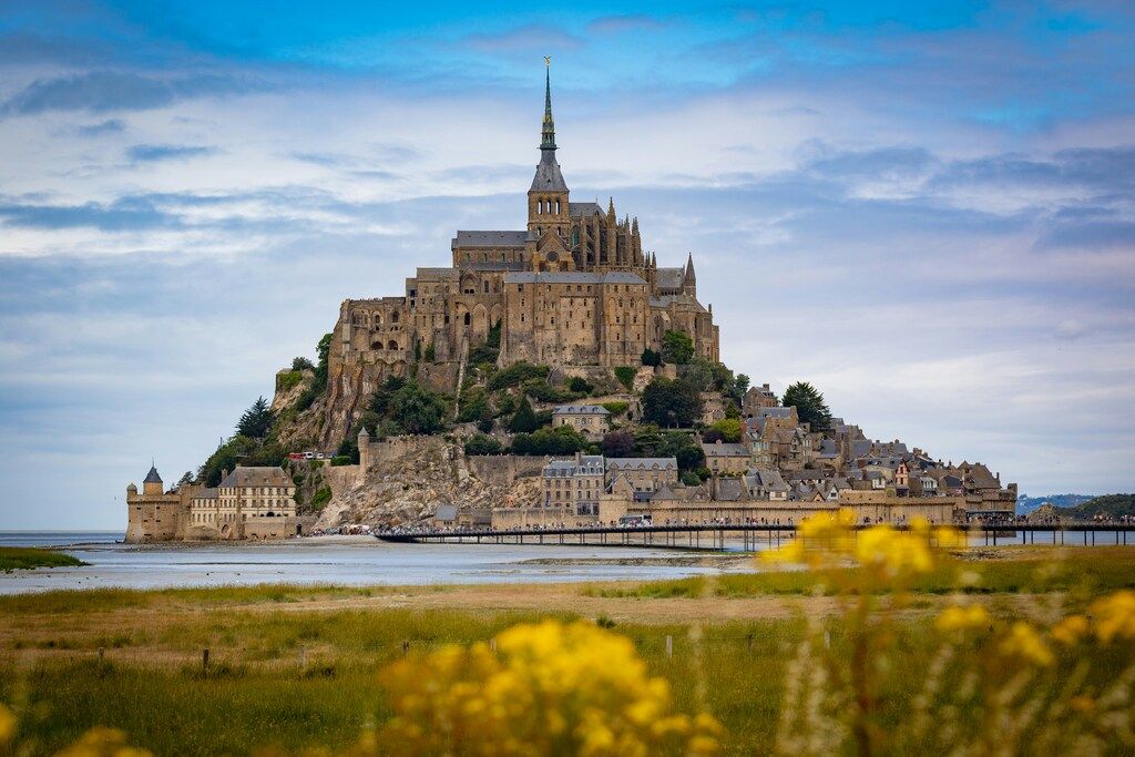 El Mont Saint-Michel emergiendo de las aguas al atardecer, rodeado de campos.