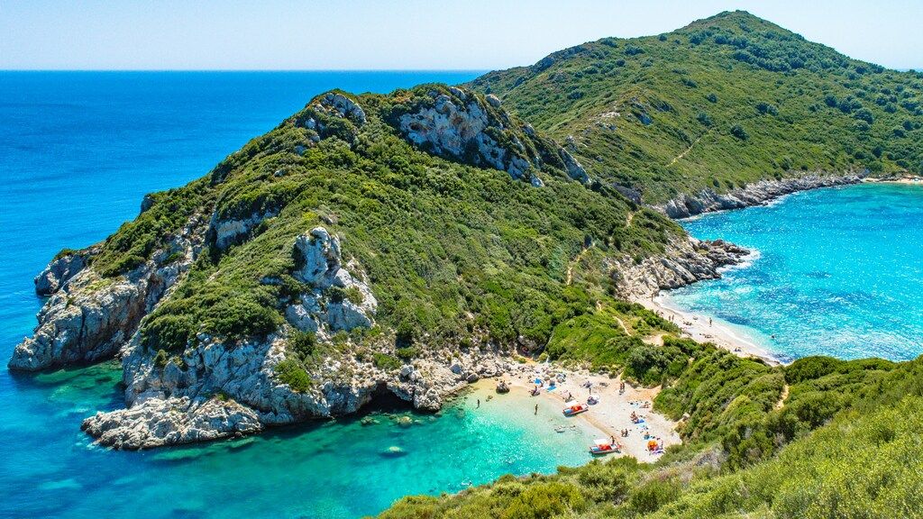 Vistas aéreas de la playa de Porto Timoni en Corfú, Grecia, con aguas turquesas y colinas verdes.