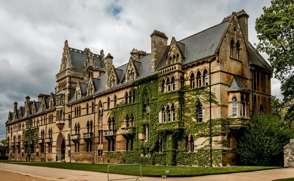 Edificio histórico cubierto de hiedra en Oxford, con arquitectura gótica y cielo nublado.