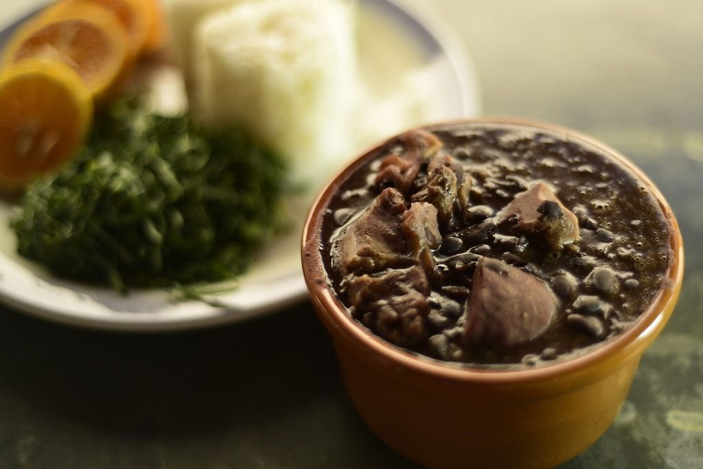Feijoada con arroz, naranjas y col rizada sobre un plato tradicional brasileño
