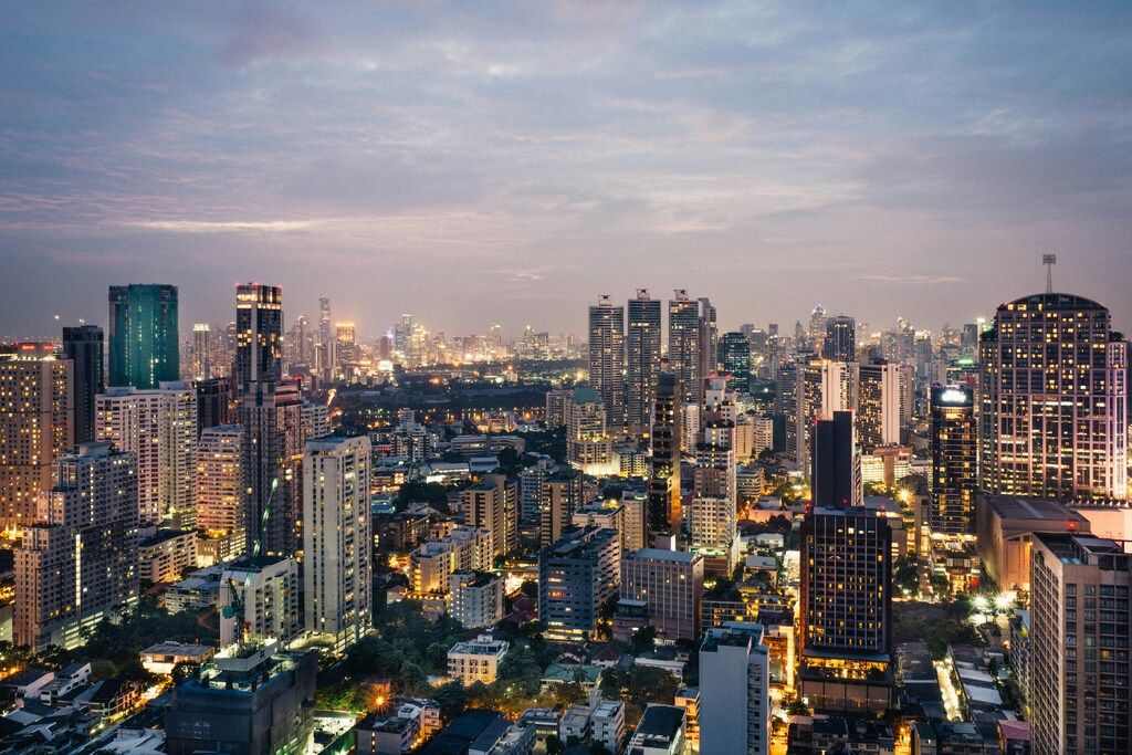 Panorama nocturno de Tailandia con rascacielos iluminados y un cielo crepuscular.