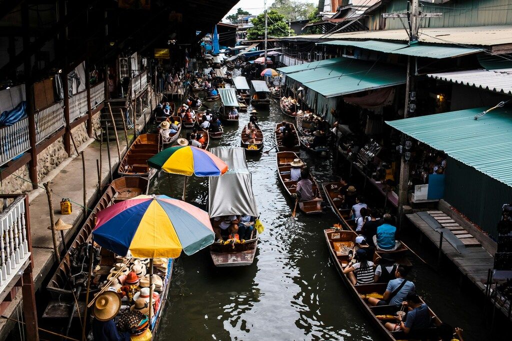 Mercado flotante con numerosos barcos y personas a lo largo de un canal estrecho.