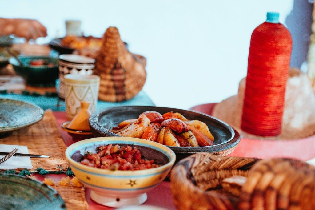 Mesa colorida servida con platos típicos marroquíes como tajín y ensaladas, lista para una comida tradicional.