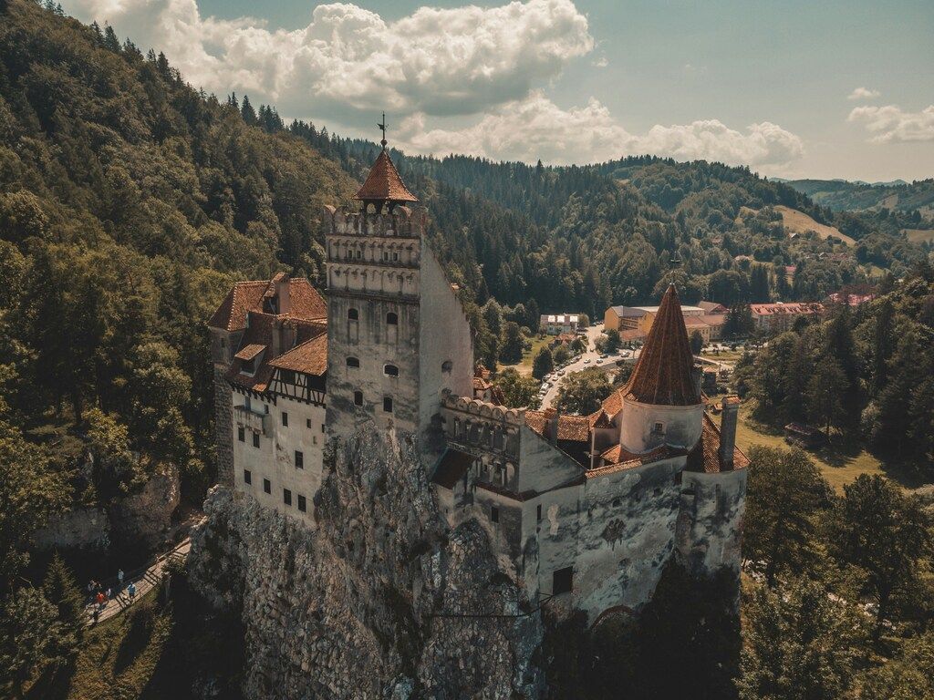 Imagen aérea del castillo de Bran en Rumanía, rodeado de bosques y montañas, famoso por la leyenda de Drácula.