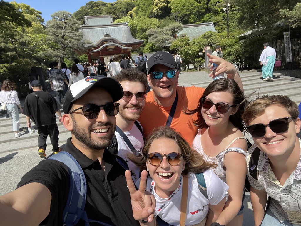 Selfie de viajeros de grupo WeRoad sonriendo frente a un santuario tradicional japonés.