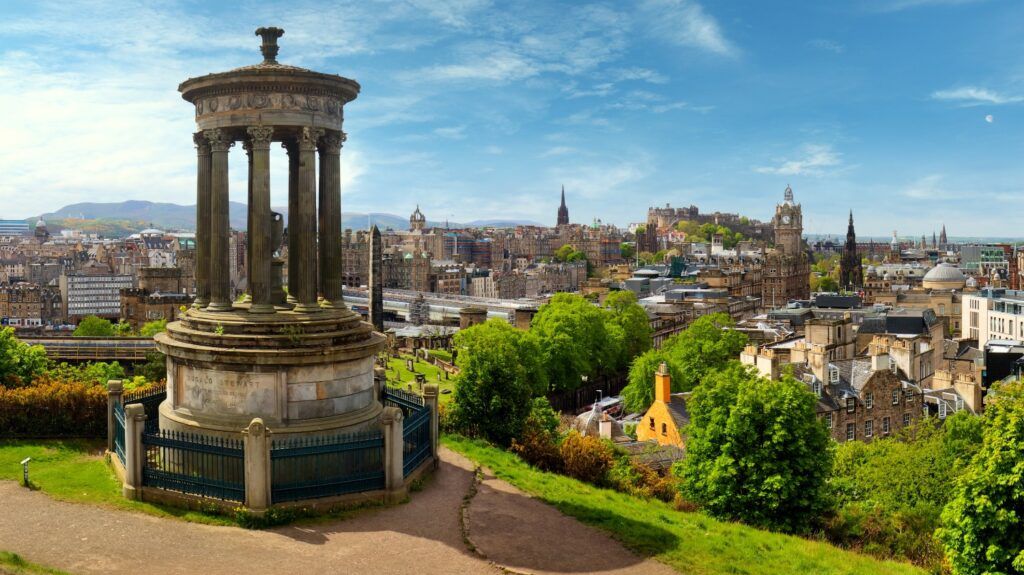 Vistas panorámicas de Edimburgo con el Monumento a Dugald Stewart en primer plano y el Castillo de Edimburgo y Calton Hill al fondo.