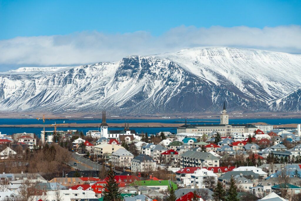 Vista panorámica de los tejados de colores de Reikiavik con el Monte Esja cubierto de nieve al fondo.