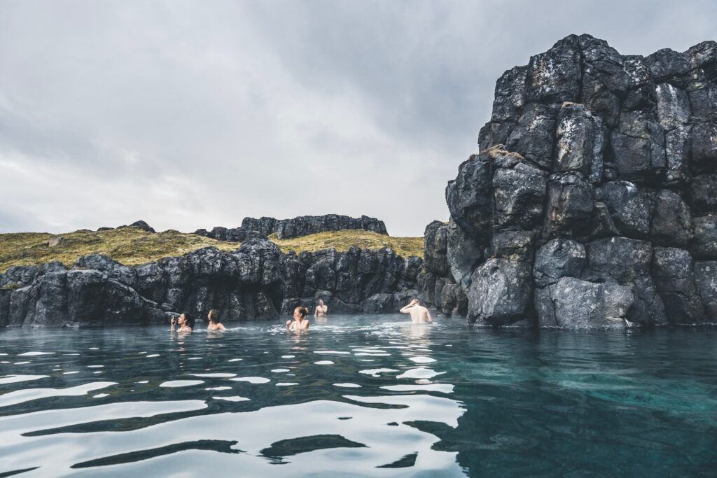 Bañistas en Myvatn Nature Baths entre rocas volcánicas y musgo.