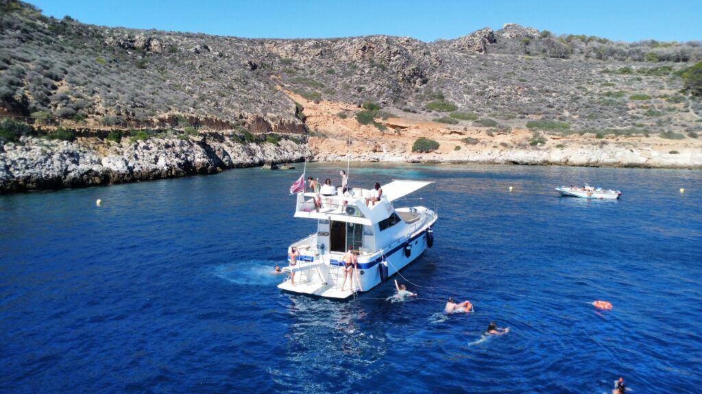 Un grupo de viajeros disfruta de un día de sol a bordo de un barco de recreo en las aguas cristalinas de la costa de Sicilia.