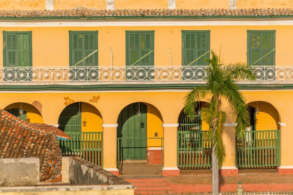 Façade coloniale jaune et orange avec des balcons en fer forgé et des volets verts du Musée Romantique à Trinidad, Cuba.
