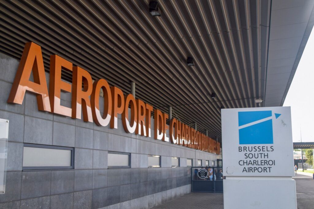 Entrada exterior y señalización del aeropuerto de Bruselas Sur Charleroi (Brussels South Charleroi Airport), con letras naranjas grandes en la fachada.